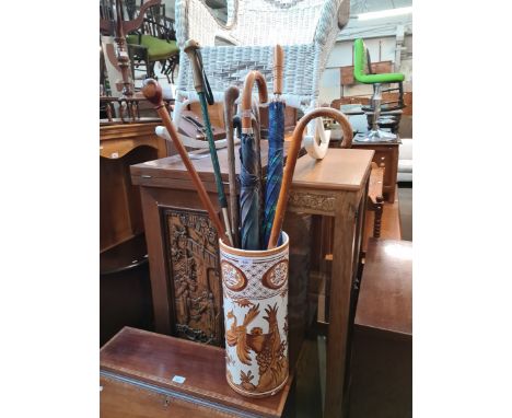 A ceramic stick stand containing a number of sticks and umbrellas. 