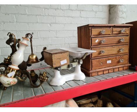 A small cabinet with glass knobs, vintage kitchen scales with weights and two ceiling light fittings. 