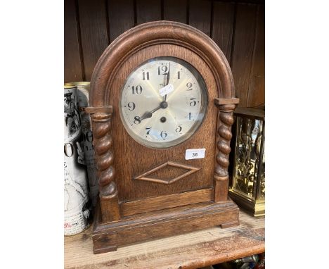 An early 20th century oak cased German 8 day mantel clock with pendulum, key and barley twist columns.