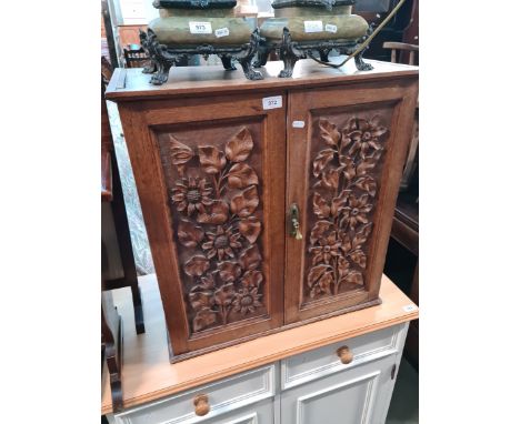 An early 20th century oak cabinet with carved panels to the doors. 