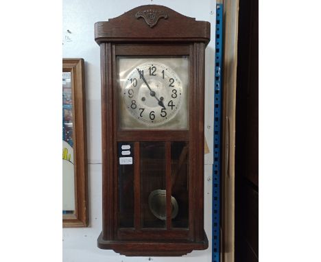 An early 20th century oak cased chiming wall clock with pendulum and key. 