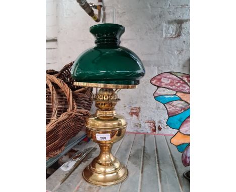 A vintage brass paraffin lamp with funnel and green glass shade. 