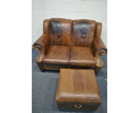 A BROWN LEATHER TWO SEATER SOFA, and an ottoman footstool (condition - dark stains to back and seat) (2)