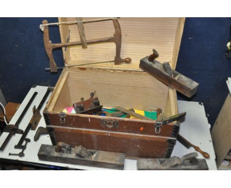 A VINTAGE TRUNK CONTAINING TOOLS to include three jack planes, plough plane, bow saw, T-square etc