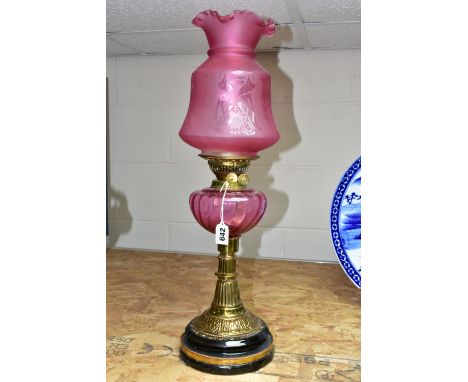 A LATE VICTORIAN BRASS BASED OIL LAMP, the domed acid etched clear and opaque cranberry shade above a cranberry reservoir, re