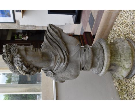 An antique stone statue bust, the subject standing on a circular plinth with scrollwork and shell decoration. The bust of a c