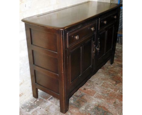 An Ercol Old Colonial dark elm side board, with two frieze drawers, over a pair of panelled cupboard doors, with latch mechan