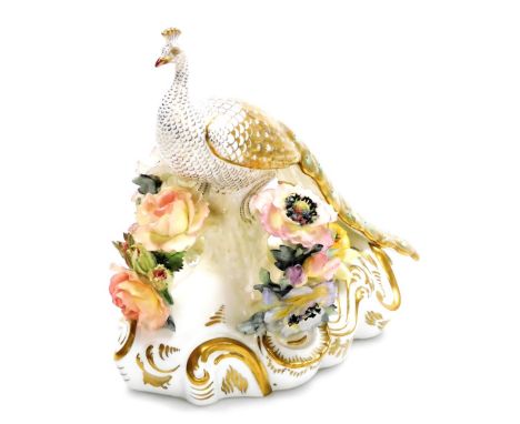 A Royal Crown Derby porcelain model of a peacock, modelled on a floral encrusted branch, on a scroll decorated base, gilt hei