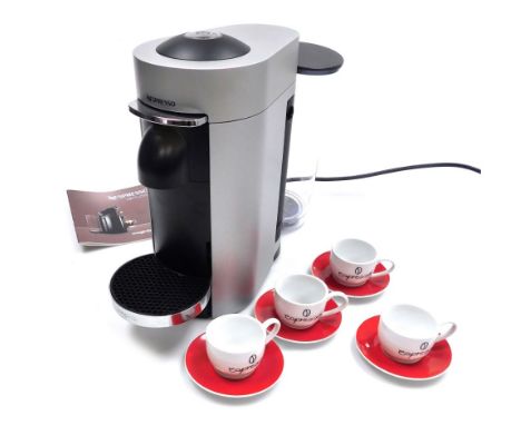 A Nespresso coffee machine, together with four espresso cups and saucers.