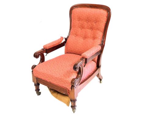 A Victorian mahogany spoon back reclining library chair, with an overstuffed button back, seat, and arms, with scroll carved 