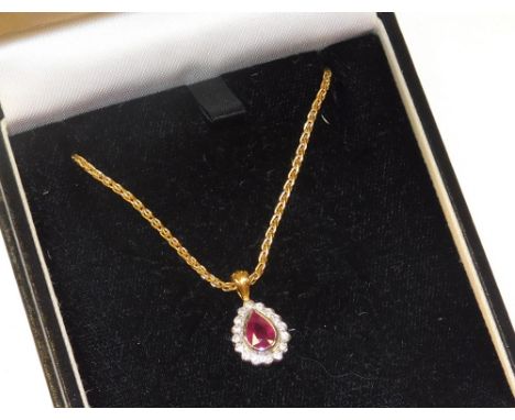 A ruby and diamond pendant, the tear drop shaped ruby in a surround of diamonds, set in white and yellow metal, on an 18ct go