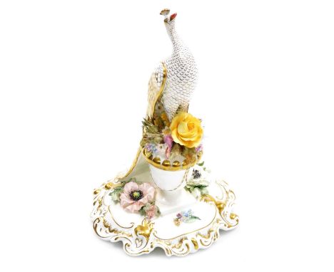 A Royal Crown Derby porcelain model of a peacock, modelled on a floral encrusted urn, on a scroll and floral decorated base, 