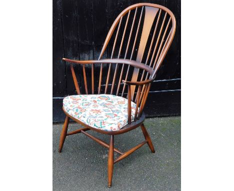 An Ercol dark elm and beech Windsor armchair, with a loose cushion seat, raised on turned legs united by a H frame stretcher,