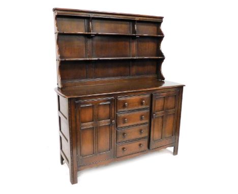An Ercol dark elm dresser, the top with a two shelved plate rack, the base with four central doors flanked by two panelled do