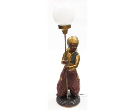 A cold painted metal lamp base, modelled as an Arab boy holding the fitting, with an opaque glass shade, 75cm high.&nbsp;Buye