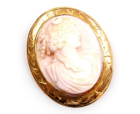 A 20thC pink coral cameo brooch, bust portrait of classical lady, in an oval yellow metal frame, foliate engraved, with safet