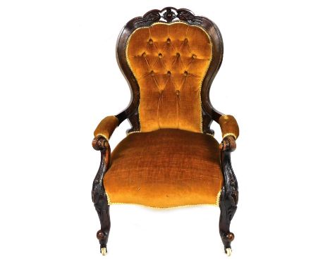 A Victorian mahogany balloon back nursing chair, with floral carved crest rail, button back upholstered in yellow draylon, ov