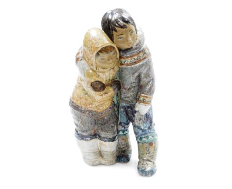A Lladro porcelain figure group of an Inuit boy and girl, modelled standing in embrace, printed marks, 38cm high.
