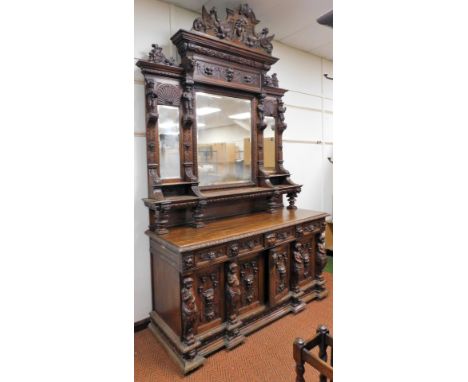 A Victorian oak mirror back sideboard, the shaped pediment carved with a mask flanked by fruit and griffins, over a similarly