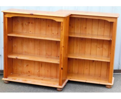 A pair of pine open bookcases, one with two additional shelves, one with one shelf, raised on a plinth base and bun feet, 106