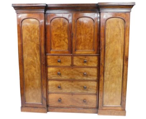 A Victorian mahogany compactum wardrobe, the top with a moulded cornice, the central section with two panelled doors enclosin