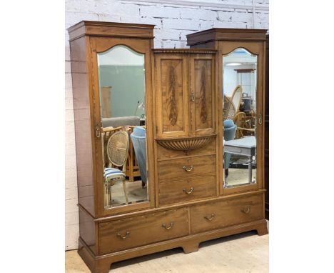 An Edwardian mahogany three part wardrobe with inlaid bow fronted centre section fitted two panel doors with hanging rail abo