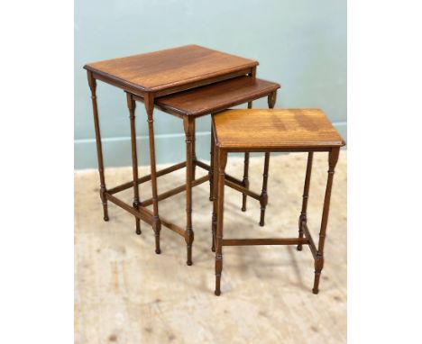 An Edwardian mahogany set of three nesting lamp tables, with shaped moulded tops, on turned supports (tallest: h. 61cm x l.51