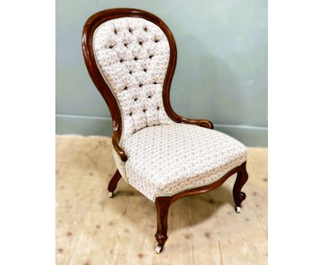 A Victorian mahogany framed slipper chair with button back on carved scroll feet with original brass caps and white ceramic c