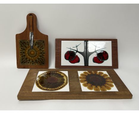 A collection of three wooden boards inlaid with tiles comprising, a long wooden board with two symmetrical panels decorated w