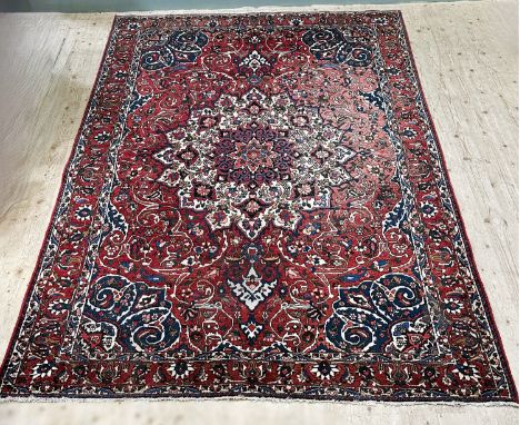 An Iranian hand woven shahrekordrug rug with centre medallion, stylized lotus flowers and scrolls and multiple flower head bo