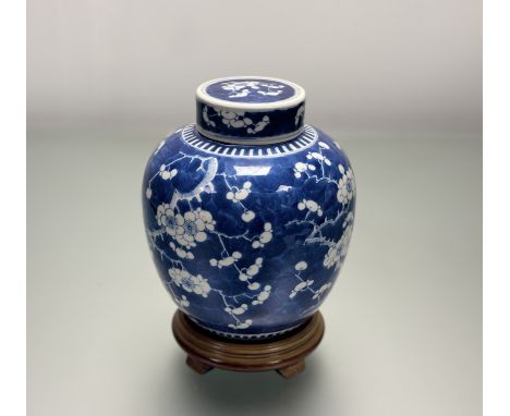 A 19thc Chinese blue and white prunus blossom ginger jar with cover, together with a circular wooden base, marked verso. (h-2