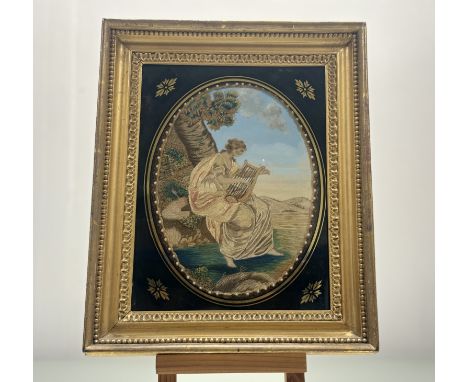 A late George III period oval needlework, embroidered in coloured silks and wools, with raised work depicting a lady playing 