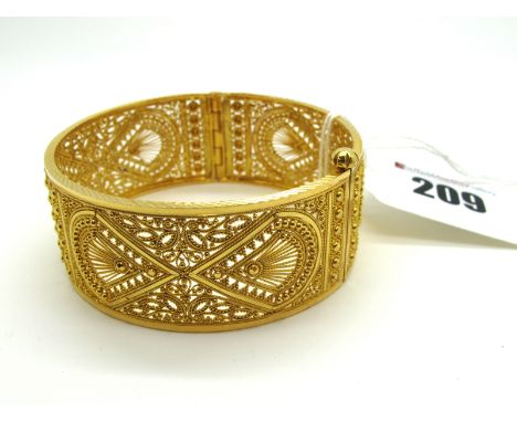 A Middle Eastern Bangle, of wide design, allover textured and pierced, hinged to screw-in pin clasp, stamped "22KDM".
