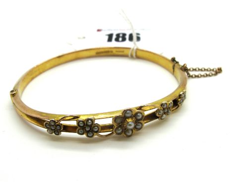 A Late Victorian 9ct Gold Pearl Set Bangle, the front composed of two knife edge bars, with applied pearl set flowerheads, hi