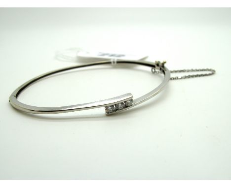 A Modern Three Stone Diamond Set Bangle, of crossover design set with uniform stones, hinged to snap clasp.