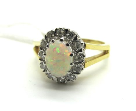 An 18ct Gold Opal and Diamond Set Cluster Ring, oval cabochon claw set to the centre, within single and brilliant cut diamond