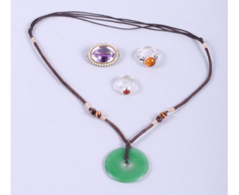 A 19th century amethyst and seed pearl brooch, a jade Pi disk, on necklace, and two silver and amber rings 