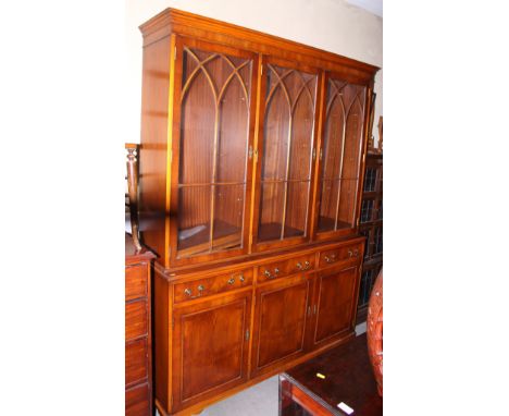 A yew wood display cabinet, the upper section enclosed three Gothic lattice glazed doors over drawers and cupboards, on brack