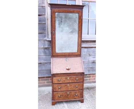 An early Georgian figured walnut and feather banded bureau bookcase, the upper section fitted drawers and pigeonholes and cup