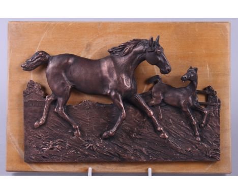 A relief moulded bronze plaque depicting a mare and foal, on wooden mount 