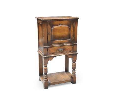 A CHAPMAN'S SIESTA OAK CUPBOARD the cupboard door with pointed-arch panel door above a drawer, raised on block and baluster l