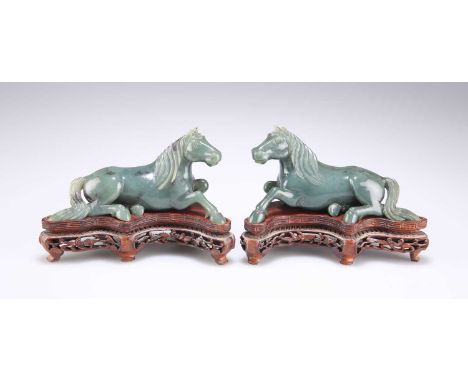 A PAIR OF CHINESE SPINACH JADE MODELS OF RECUMBENT HORSES mid-20th Century, on wooden stands. (2) 14.5cm wide overallA few mi