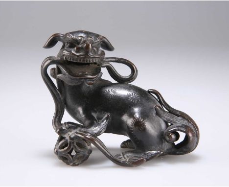 A CHINESE SMALL BRONZE BUDDHIST LION, MING DYNASTY cast with its left forepaw resting on a reticulated brocade ball, its head