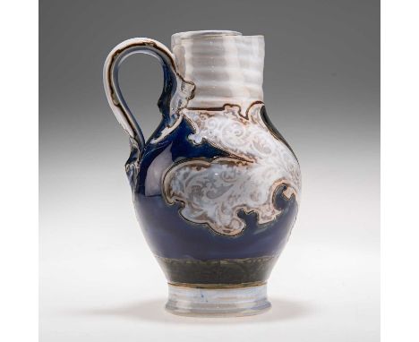 MARK V. MARSHALL FOR DOULTON LAMBETH, AN EARLY 20TH CENTURY STONEWARE JUG of baluster form with a masked handle, decorated wi