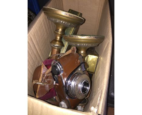 A box of misc items including brass candlesticks, brass clocks, glassware, a Kodak camera, etc 