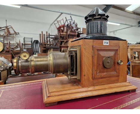 A MAHOGANY AND BRASS MAGIC LANTERN NOW POWERED BY AN ELECTRIC LIGHT, THE LENS. Dia. 4cms. TOGETHER WITH A BOX OF SLIDES DEPIC