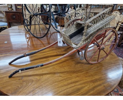 A SCALE MODEL DOG CART WITH WICKER SIDES ABOUT THE WOODEN SEAT, IRON TREADS TO THE TWO SPOKED WHEELS