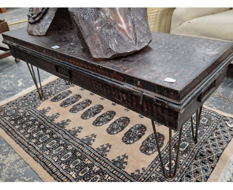 AN OFFICERS TIN TRUNK MOUNTED ON WIRE WORK LEGS AS A COFFEE TABLE