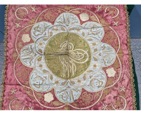 AN OTTOMAN GOLD AND SILVER THREAD ON SILK PANEL WITH A CENTRAL TUGHRA ON GREEN SILK WITHIN A BLUE SILK FLOWER HEAD AND PINK S