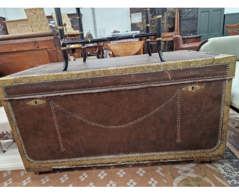 A CLOSE NAILED AND BRASS CORNERED LEATHER BOUND CAMPHOR WOOD TRUNK WITH HANDLES TO EACH NARROW END AND ON CASTER FEET.   W 11